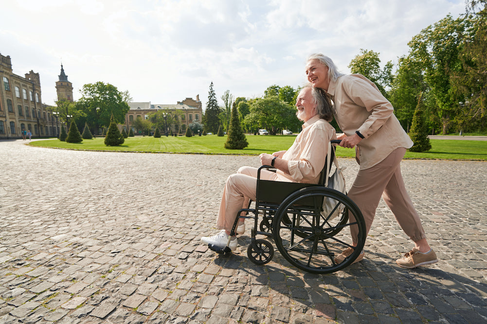 elderly couple woman pushing elderly man in wheelchair