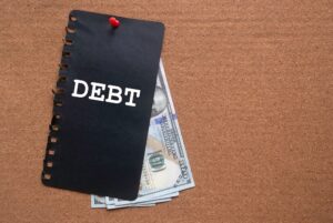 Words debt on a cover with money under