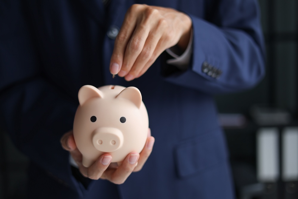 Person putting in money in a piggy bank
