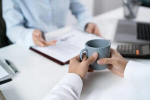 Person looking over paperwork with a cup of coffee