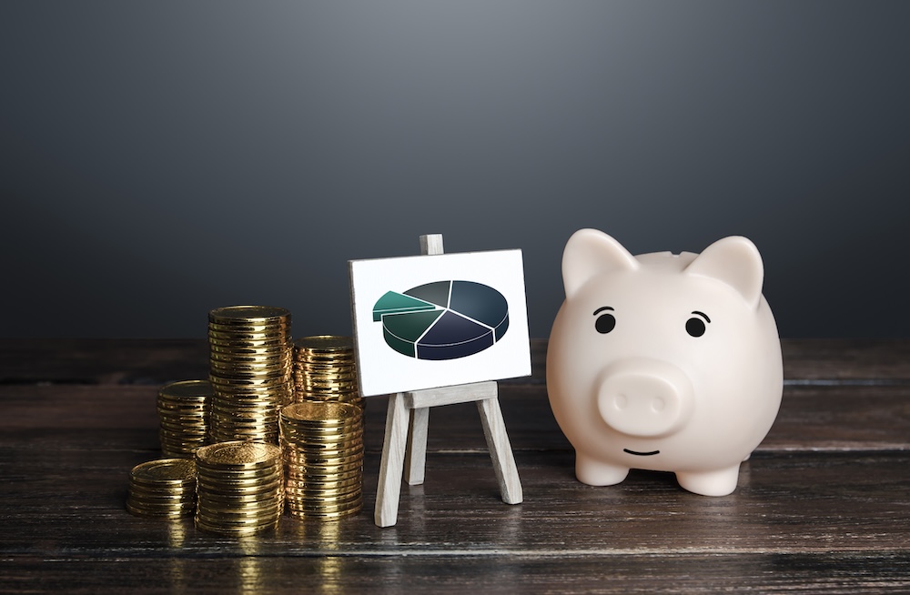 Stacked coins, a chart, and a piggy bank